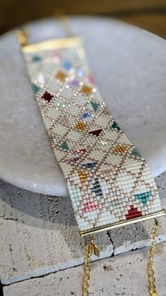 a white plate topped with a gold chain and beaded bracelet on top of it