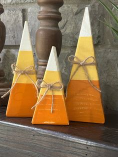 three orange and white wooden cones tied with twine on top of a wood shelf