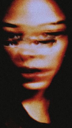 a blurry image of a woman's face with her eyes closed and one eye partially open