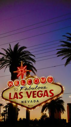 the welcome to fabulous las vegas sign is lit up at night with palm trees in the background