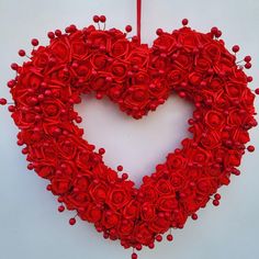 a heart shaped wreath with red roses hanging on a wall in the shape of a heart