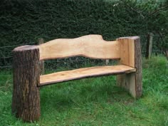 a wooden bench sitting on top of a lush green field next to a tree stump