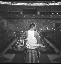 a man standing on top of a bench in front of an arena filled with people