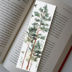 an open book with a watercolor painting of trees and birds on the page,