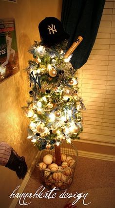 a baseball themed christmas tree with lights and balls in a basket, next to a window