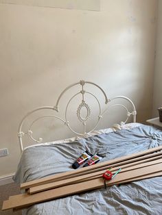 a white bed with wooden slats and some construction tools laying on top of it