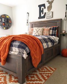 a bed room with a neatly made bed and an orange blanket