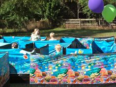 several children are playing in an outdoor play area with blue tarps and colorful decorations