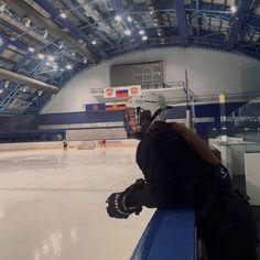 a woman sitting on top of a bench next to an ice rink