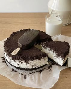 a chocolate cake with ice cream and oreo cookies on it next to a glass of milk