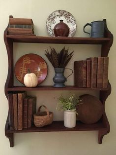 a shelf with books, vases and other items on it next to a wall