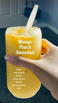 a hand holding a glass with mango peach smoothie in it's mouth and the words mango peach smoothie written on it