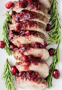 sliced pork with cranberry sauce and rosemary sprigs