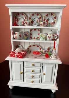 a white china cabinet with plates and cups on it