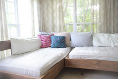 a couch with pillows on it in front of a window and curtained windowsill