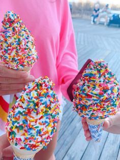 two people holding ice cream cones with sprinkles