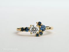 a three stone ring with blue and white stones on the side, set in yellow gold