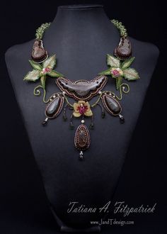 an elaborate necklace is displayed on a mannequin's neckline with flowers and leaves