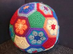 a multicolored crocheted ball sitting on top of a black couch next to a wall