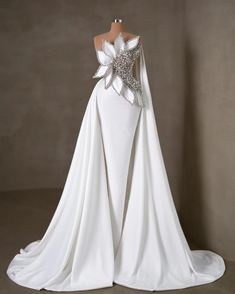 the back of a white wedding dress with silver sequins and flowers on it