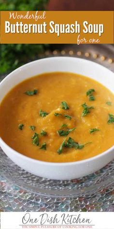 a white bowl filled with butternut squash soup on top of a glass tablecloth