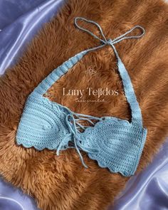 a teddy bear laying on top of a bed wearing a blue bikinisuit with crochet