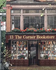 the corner bookstore has many books on it's windows and is surrounded by greenery