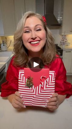 a woman in a red dress holding up a christmas present