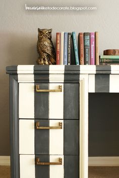 an owl statue sitting on top of a black and white striped desk next to books