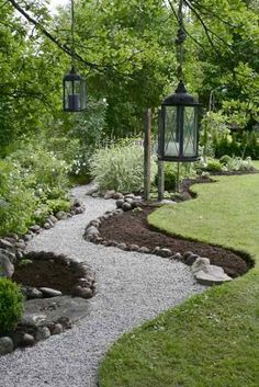 an image of a garden with rocks and gravel in the foreground, along with two hanging lanterns