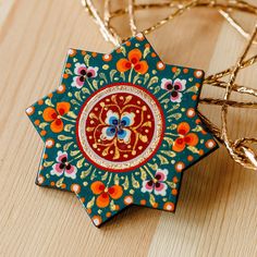 an ornament is sitting on a table next to some gold wire and flowers