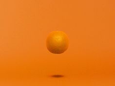 an orange is floating in the air on a yellow background