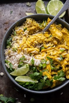 a bowl filled with rice, chicken and cilantros next to lime wedges