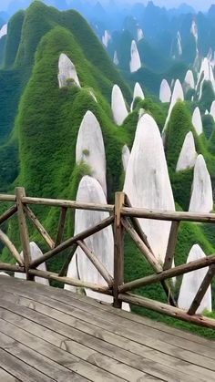 a wooden walkway leading to the top of a mountain with green mountains in the background