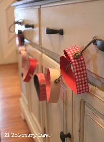 the kitchen cabinets are decorated with red and white paper hearts hanging from hooks on them