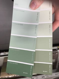 a person holding up some green and white paint samples in their left hand, with the same color swatches on each side