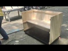 a wooden cabinet sitting on top of a sidewalk next to a man walking past it