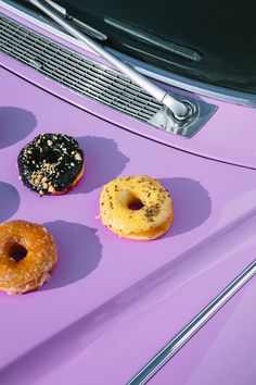 three donuts sitting on top of a purple table next to a black grill grate