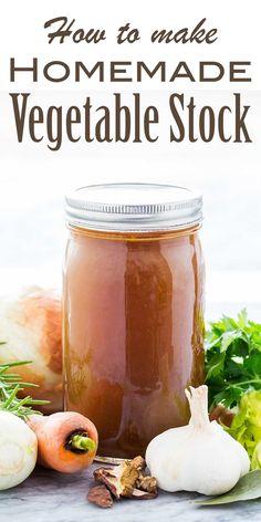 a jar filled with homemade vegetable stock sitting on top of a table next to vegetables