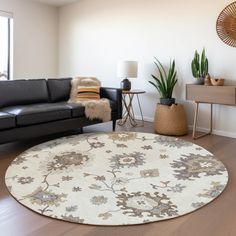 a living room with black leather couches and a white round rug on the floor