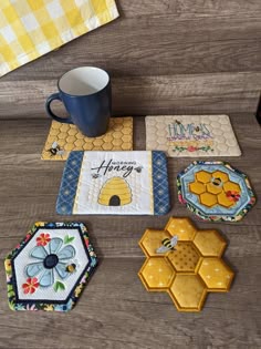 four coasters with bees and honeycombs on them next to a coffee cup