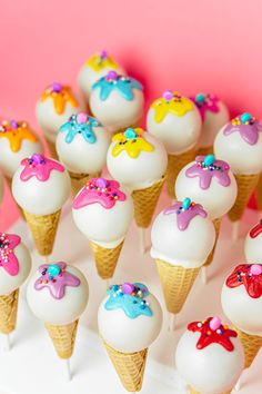 cupcakes with white frosting and colorful decorations are arranged on a pink surface