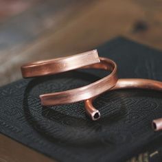 two copper bracelets sitting on top of a book