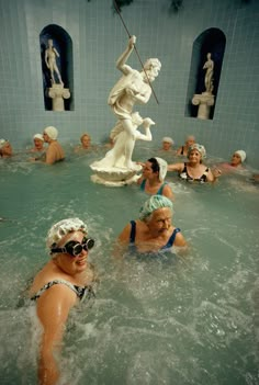 some people are swimming in a pool with statues