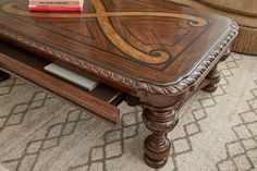 a coffee table with a book on top and a chair in the back ground next to it