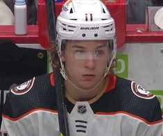 the hockey player is waiting for his turn to play in the game, and he's looking at the camera