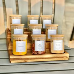 six jars of honey sit on a wooden tray next to each other with labels in them