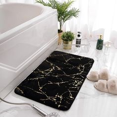 a black and gold bathroom rug next to a bathtub with plants in the background