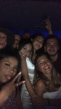 a group of young people posing for a photo at night with their fingers in the air