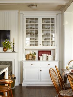 a white china cabinet with glass doors in a dining room